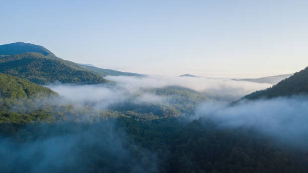 istock Epic Aerial Flight Through Mountain Clouds on Sunrise Beautiful Morning. 1006462904