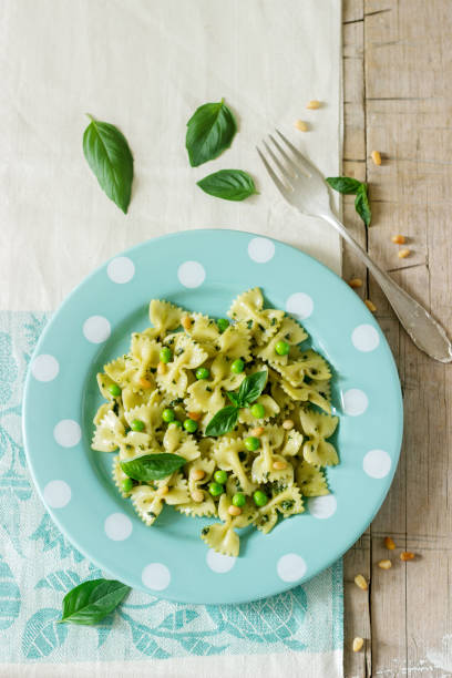 istock Pasta with pesto sauce, green peas and basil on a wooden table. Rustic style. 1006463368