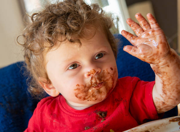 istock baby is eating a chocolate cake 1006466408