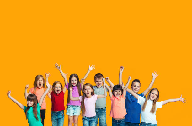 Happy success teensl celebrating being a winner. Dynamic energetic image of happy children We won. Winning success happy teen girls and boys celebrating being a winner. Dynamic image of caucasian Children on orange studio background. Victory, delight concept. Human facial emotions concept. Trendy colors cheerful children stock pictures, royalty-free photos & images