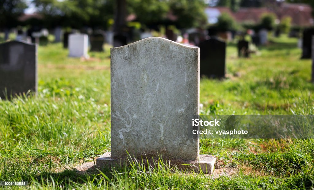 Blank gravestone with other graves in the background Stone, old, mottled Tombstone Stock Photo