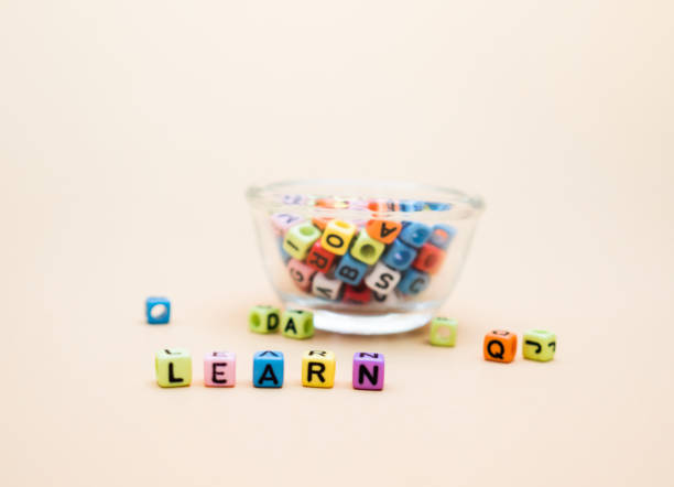 istock Learn : Colorful cube letters  Glass cup on orange Background. 1006485104