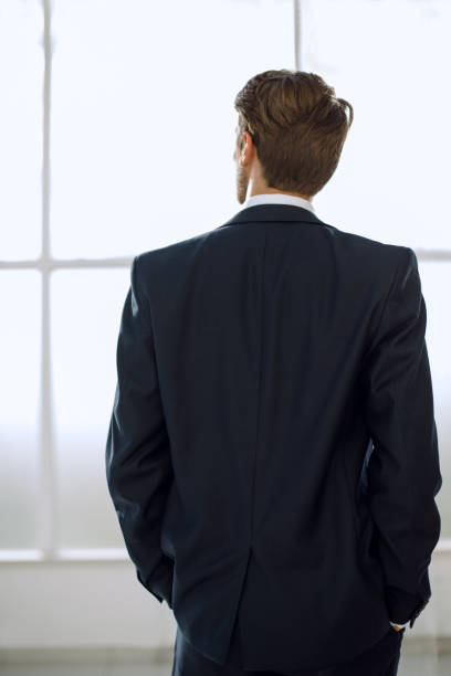 istock rear view.business man looks out the office window 1006485934