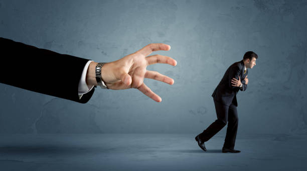 istock Business man running away from a huge hand concept 1006496506