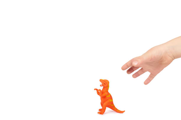 istock Prehistoric dinosaur rubber toy with kid hand, isolated on white background. copy space template 1006503696