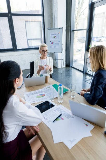 istock beautiful businesswomen sitting at table with documents during meeting in office 1006512238