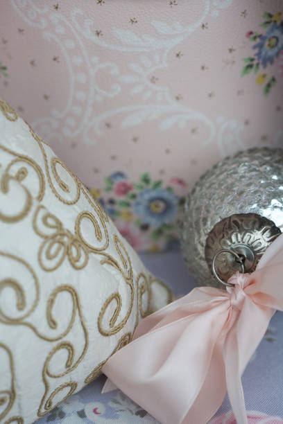 istock Winter Holiday silver ornament with pink bow against gold white and pink patterned fabric background 1006528356
