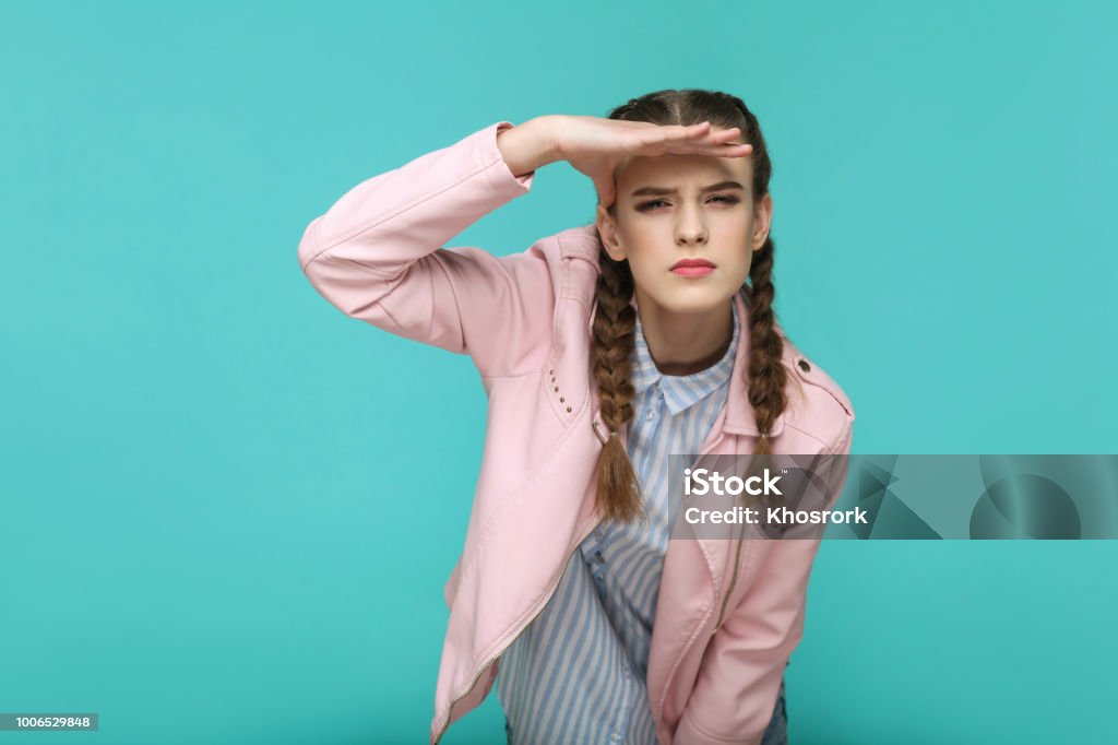 vous cherchez trop loin. Portrait de belle jolie fille debout avec maquillage et coiffure brun queue de cochon en veste rayée chemise bleu clair et rose. - Photo de Chercher libre de droits