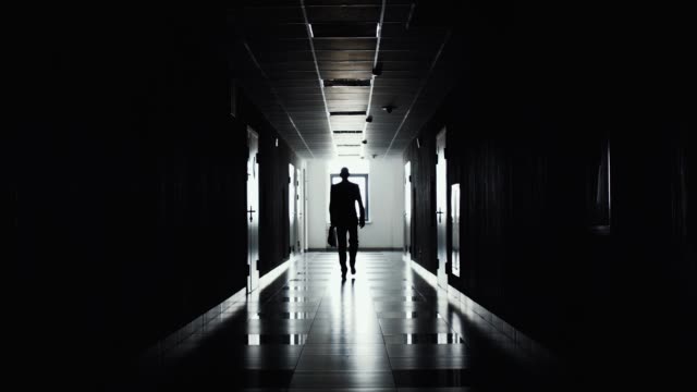 Silhouette of businessman walking along the corridor.