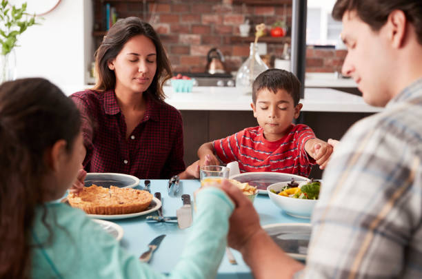 istock Family Praying Before Meal Around Table At Home 1006538518