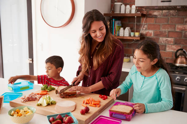 kinder helfen mutter machen schulessen in küche zu hause - kochen stock-fotos und bilder