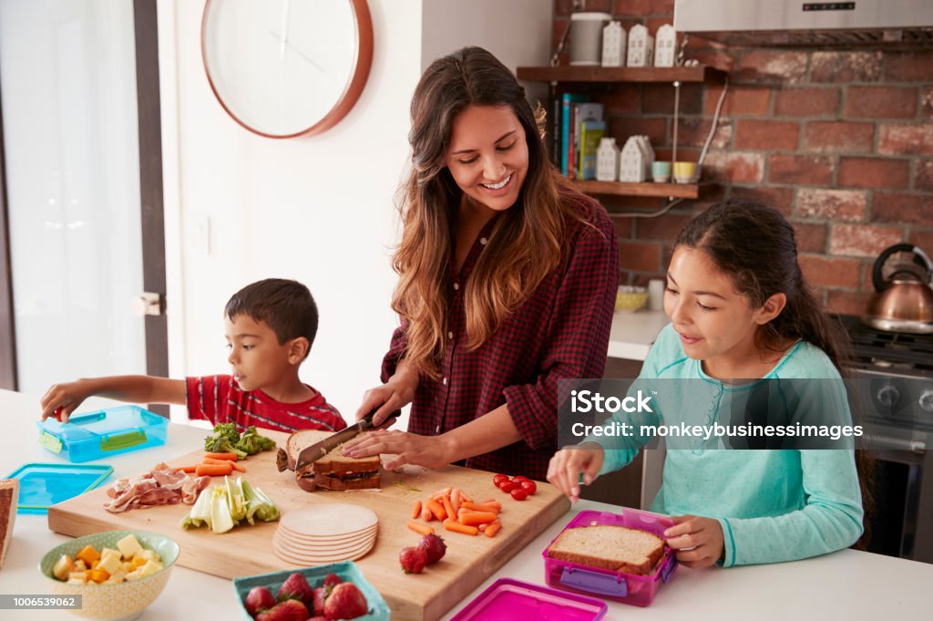 Mère d’aider enfants aux cantines scolaires de faire dans la cuisine à la maison - Photo de Enfant libre de droits