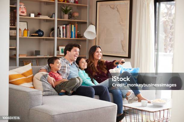 Famiglia Rilassante Sul Divano A Casa Guardando La Televisione - Fotografie stock e altre immagini di Famiglia
