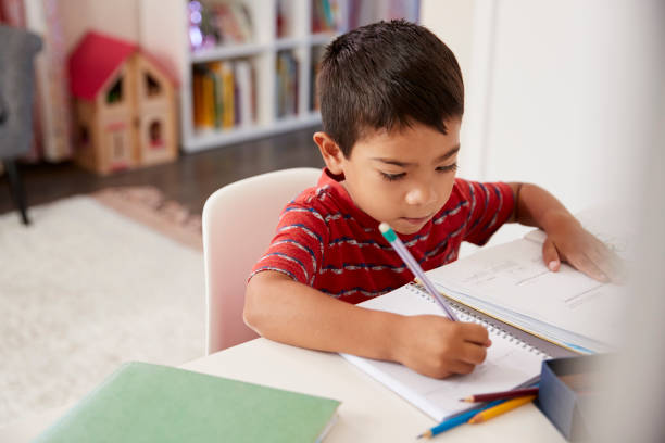 istock Young Boy Sitting At Desk In Bedroom Doing Homework 1006542624