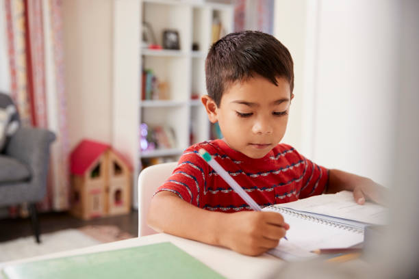 istock Young Boy Sitting At Desk In Bedroom Doing Homework 1006543014