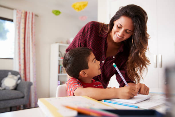 aider les fils à faire leurs devoirs, assis au bureau dans la chambre de la mère - son photos et images de collection