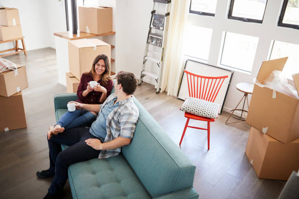 istock Happy Couple Resting On Sofa Surrounded By Boxes In New Home On Moving Day 1006547068