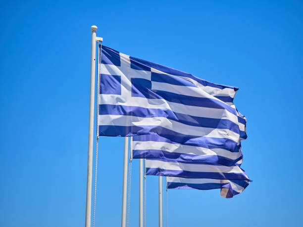 istock Official flags of Greece waving on a blue sky. 1006549952