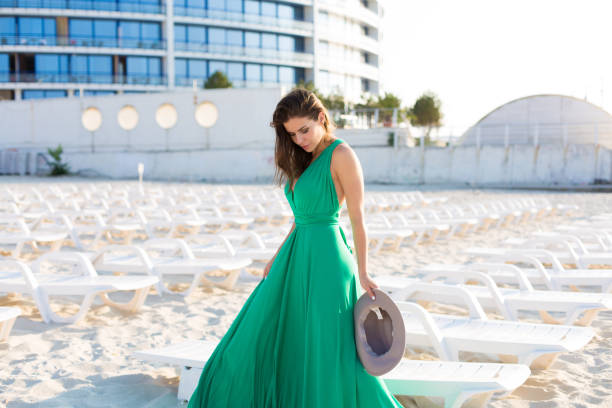 Beautiful woman in a green gown on the beach Beautiful young woman in a green gown on the beach maxi length stock pictures, royalty-free photos & images