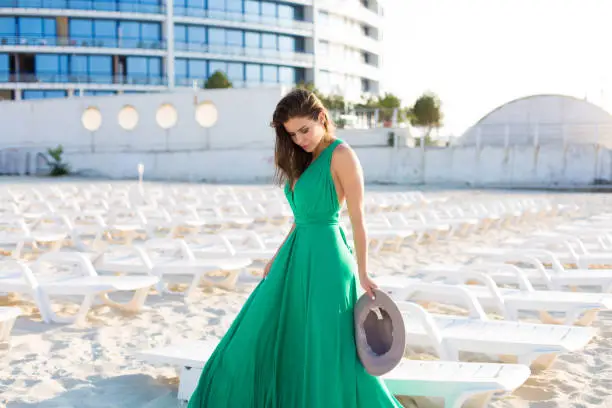 Beautiful young woman in a green gown on the beach