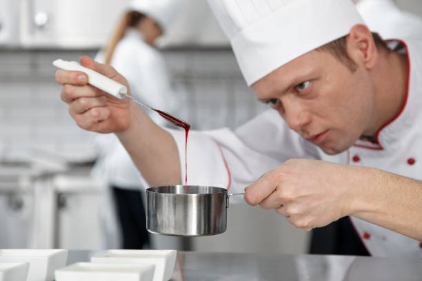männliche pastry chef dekoration dessert - konditor stock-fotos und bilder
