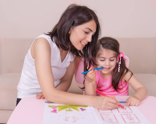 istock Mother and daughter study activity book with pencils on paper 1006559078