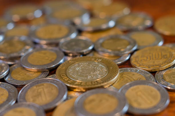 Pile of Mexican coins in the middle on a table of wood stock photo