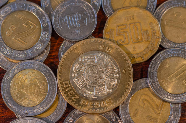 Mexican Coin in the middle of other coins on a table of wood stock photo