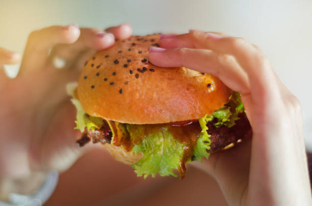 Hand with a tasty hamburger with lettuce stock photo