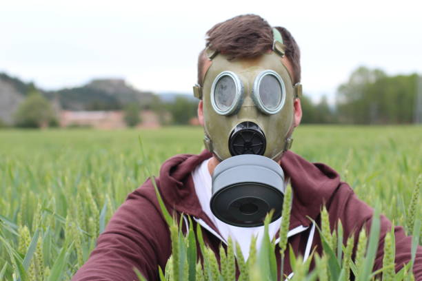 mężczyzna ubrany w maskę oddechową na polu pszenicy - toksyczna istota zdjęcia i obrazy z banku zdjęć