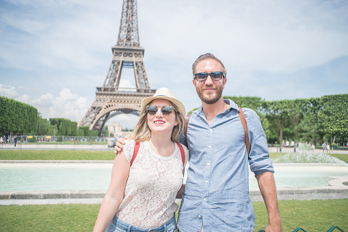 Two people at the Eiffel Tower in Paris during Springtime in sunny day. People travel discovery city concept\nYoung caucasian women tourist in Paris