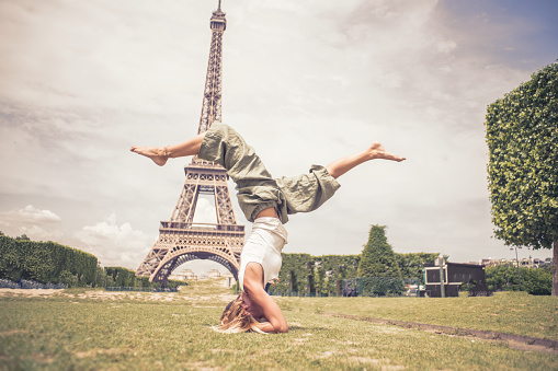 Yoga handstand of  One girl at the Eiffel Tower in Paris during Springtime in sunny day. People travel discovery city concept\nYoung caucasian woman tourist in Paris