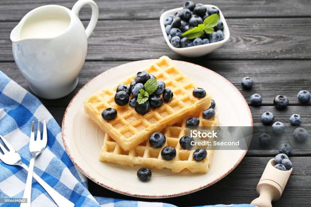 Sweet waffle with bluberries and jar of milk on black wooden table Baked Stock Photo