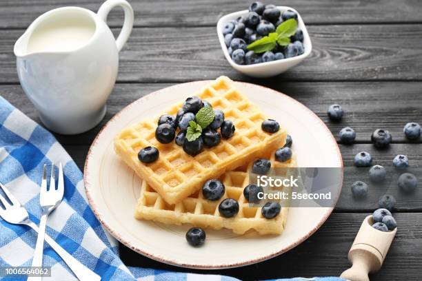 Sweet Waffle With Bluberries And Jar Of Milk On Black Wooden Table Stock Photo - Download Image Now