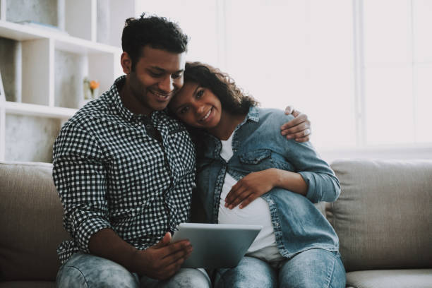 istock Young Pakistani Man with Pregnant Wife on Sofa. 1006566870