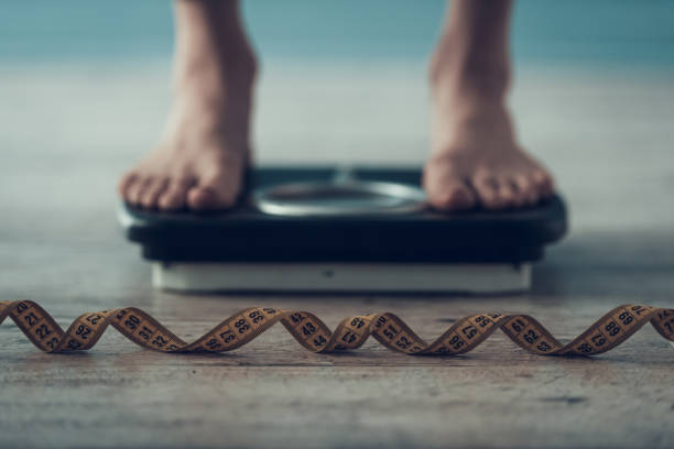 istock Close up. Young Woman Standing on Weigher on Floor 1006566912