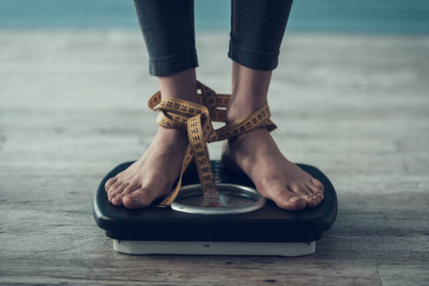 istock Close up. Young Woman Standing on Weigher on Floor 1006566934