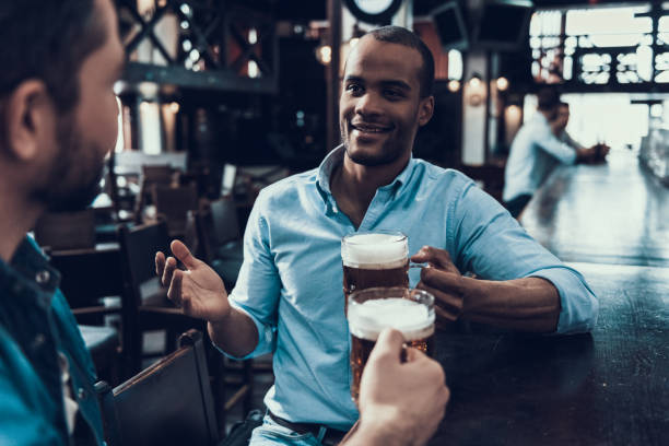 istock Young Smiling Men Drinking Beer in Modern Bar. 1006567050