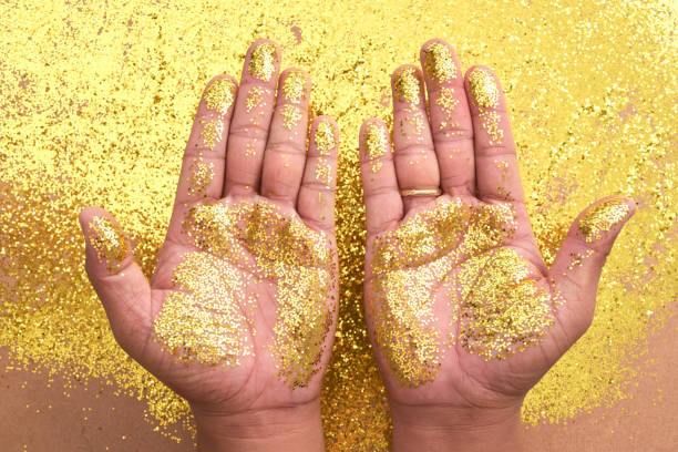 istock Crop hands in vivid golden glitters 1006570738