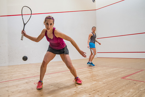 Two female player playing squash game.