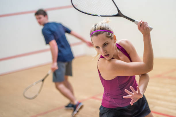 Young man and woman playing squash game Young male and female player playing squash game. squash sport stock pictures, royalty-free photos & images