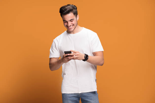 istock Smiling handsome man with mobile phone on yellow background. 1006571762