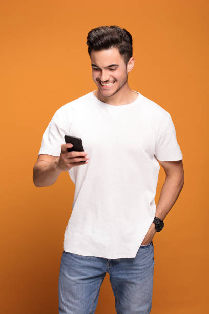 istock Smiling handsome man with mobile phone on yellow background. 1006571770