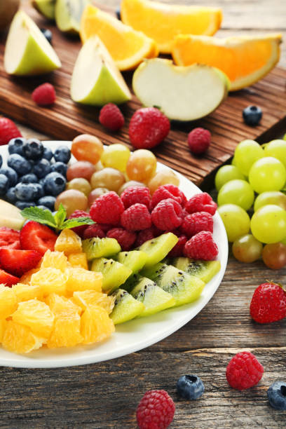 istock Fresh fruits in plate with cutting board on grey wooden table 1006573942