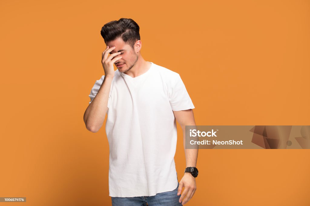 Disappointed young man on yellow background. Handsome young disappointed man on yellow studio background. Emotional facial expression. Disappointment Stock Photo