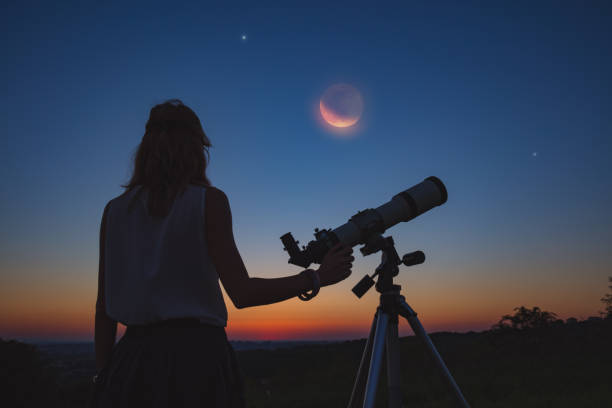 istock Girl looking at lunar eclipse through a telescope. My astronomy work. 1006575100