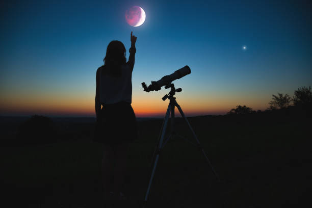 istock Girl looking at lunar eclipse through a telescope. My astronomy work. 1006578542