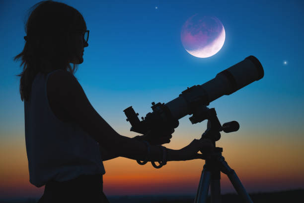 istock Girl looking at lunar eclipse through a telescope. My astronomy work. 1006579194