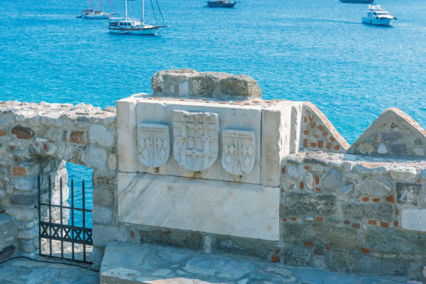 Cross and other signs carved into the wall of ancient Roman marble sculpture in Castle of St. Peter or Bodrum Castle, Turkey.