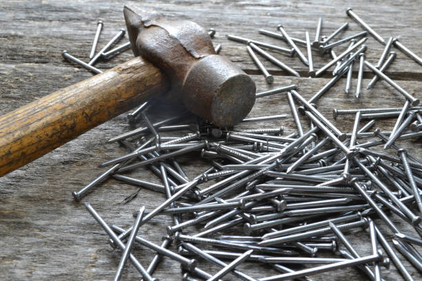 istock Nails and a hammer on an old wooden table. 1006593720